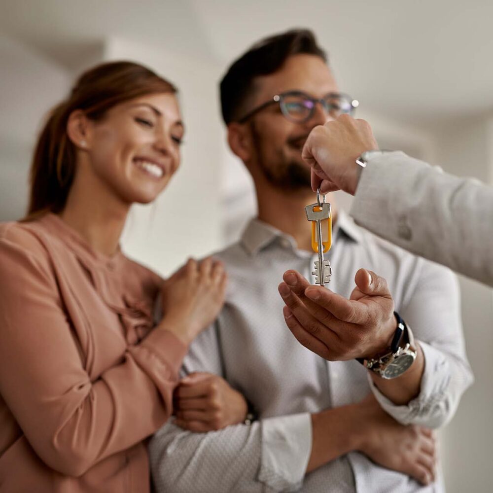 closeup real estate agent giving couple keys their new home 2